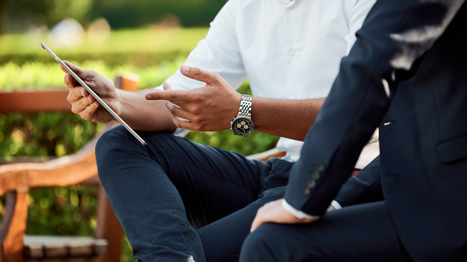 En mann holder en iPad med en Breitling på armen.